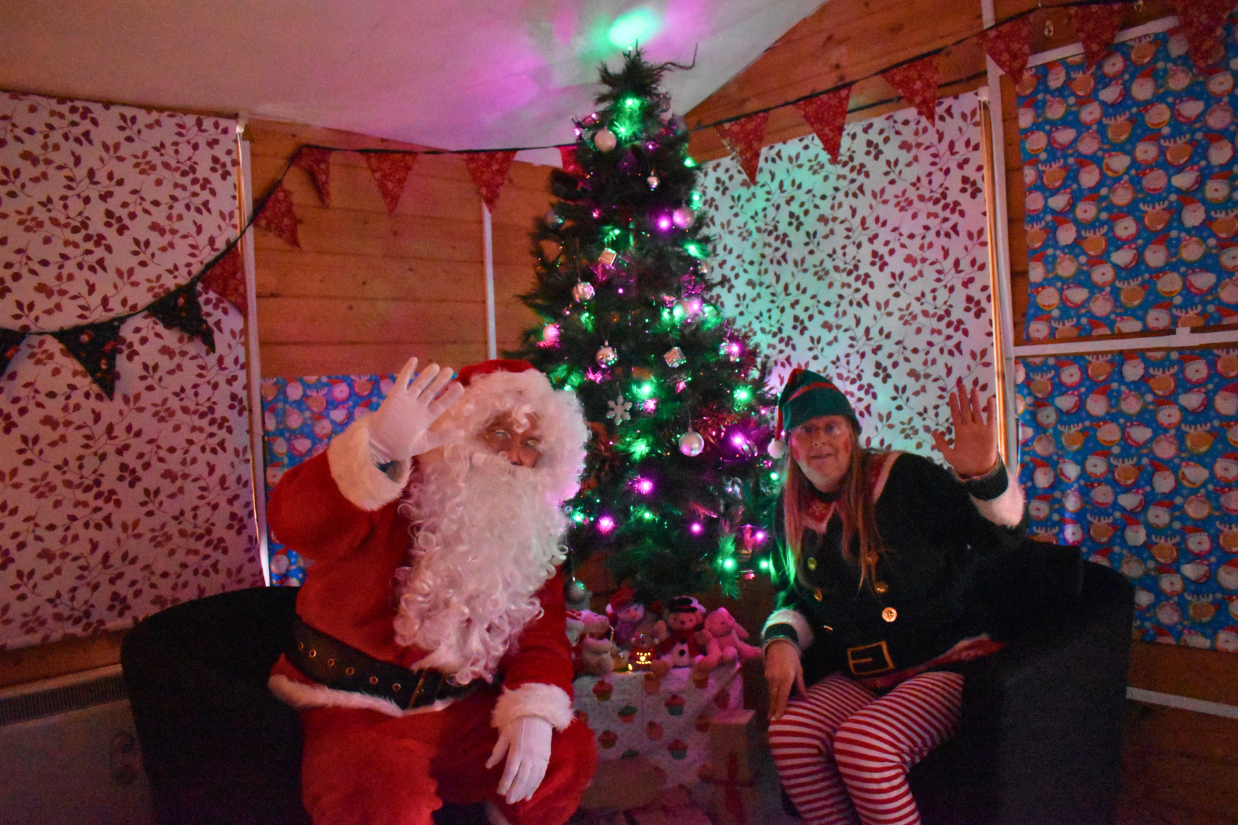 Christmas Fayre: Santa and an elf sit in front of a brightly lit Christmas Tree